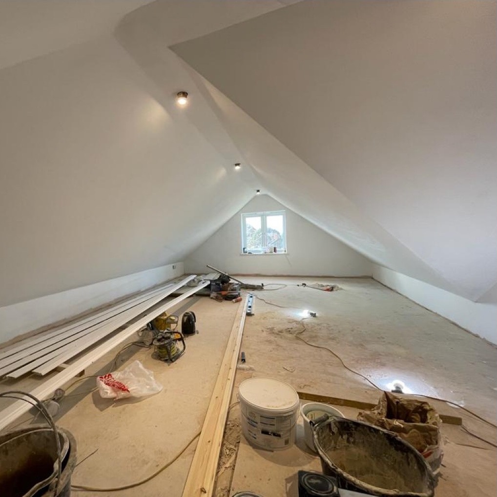 A loft converted into a bright plastered room with spotlights