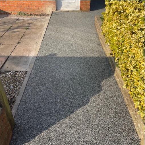 A new grey resin front path beside a golden hedge